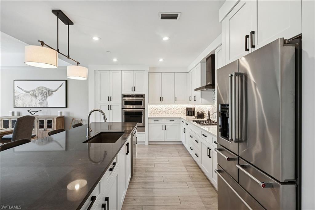 1135 3rd Avenue South, Unit 119 Naples, FL 34102 - Photo 15 of 50 a kitchen with white cabinets and stainless steel appliances