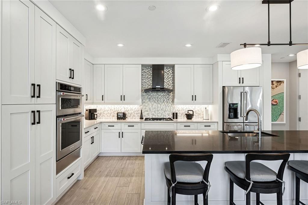 1135 3rd Avenue South, Unit 119 Naples, FL 34102 - Photo 16 of 50 a kitchen with stainless steel appliances granite countertop a stove a sink a microwave a refrigerator and white cabinets with wooden floor