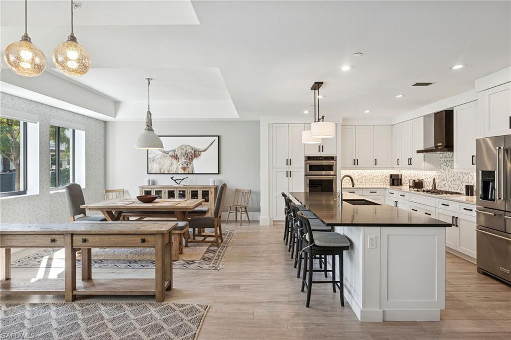 1135 3rd Avenue South, Unit 119 Naples, FL 34102 - Photo 4 of 50 a kitchen with stainless steel appliances kitchen island granite countertop a stove a sink a dining table and chairs