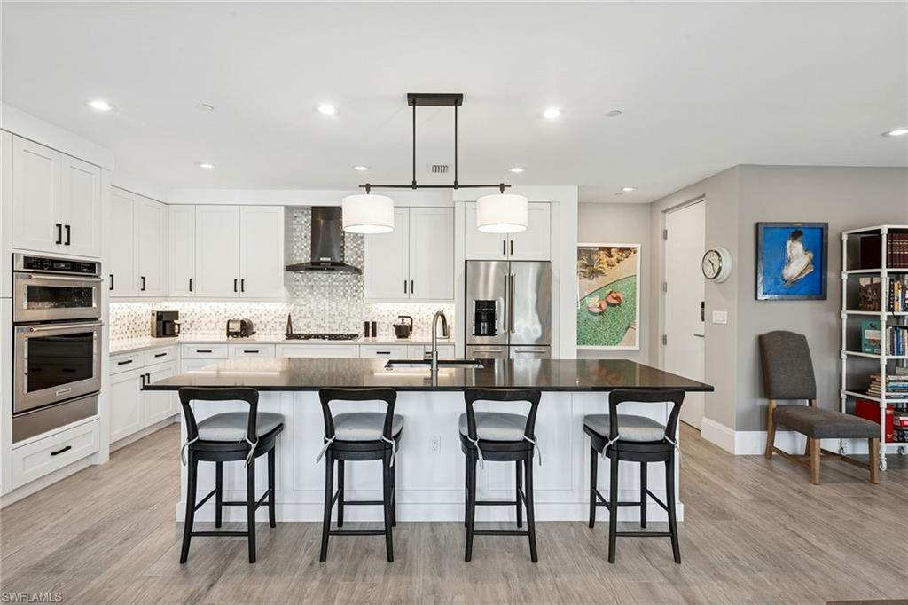 1135 3rd Avenue South, Unit 119 Naples, FL 34102 - Photo 8 of 50 a kitchen with stainless steel appliances kitchen island granite countertop a dining table chairs and white cabinets