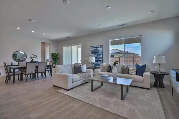 a living room with furniture kitchen view and a wooden floor