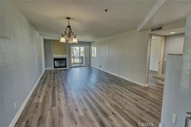 an empty room with wooden floor fireplace and windows