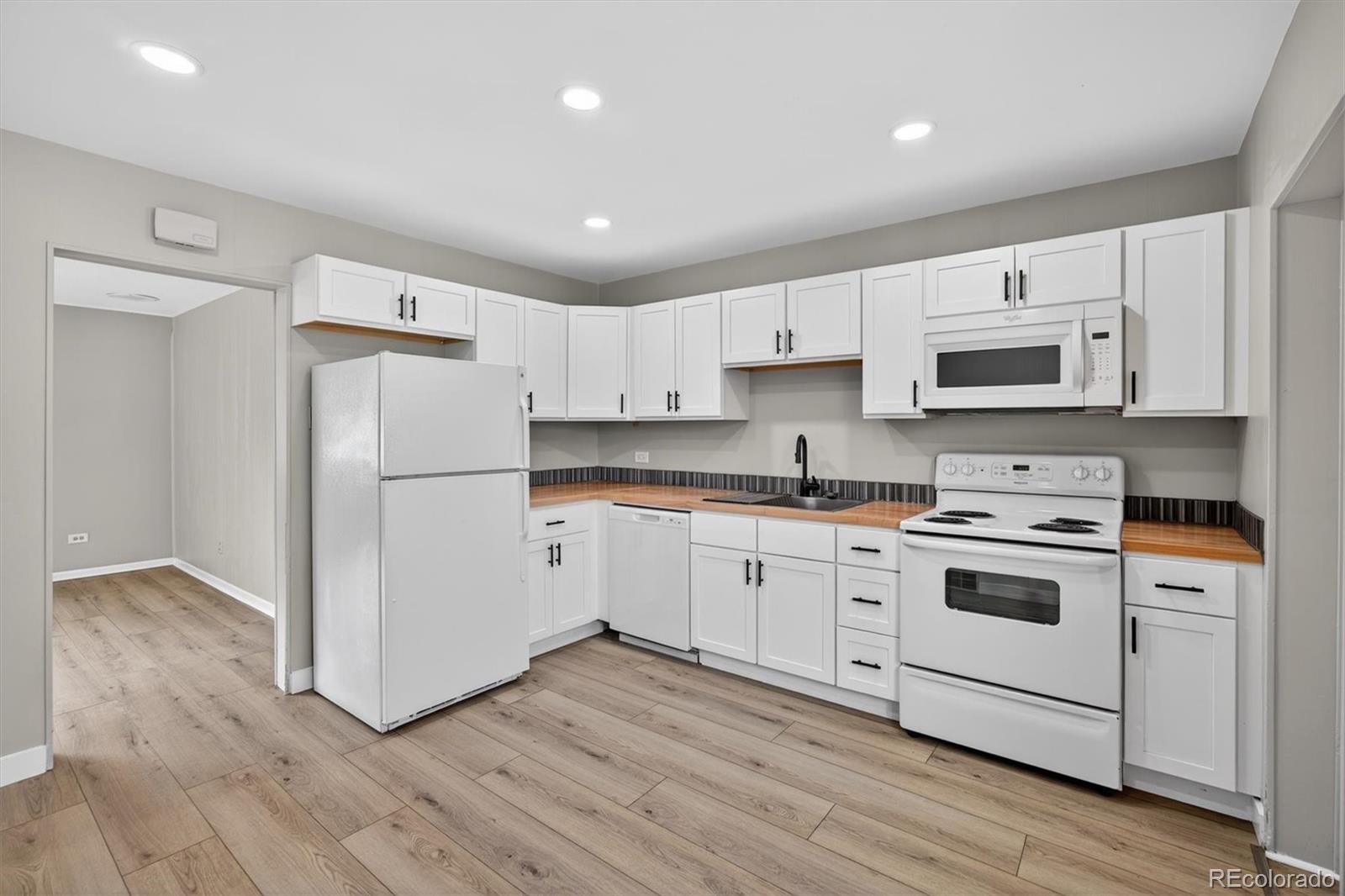 705 Perry Street Denver, CO 80204 - Photo 7 of 23 a kitchen with white cabinets white stainless steel appliances and wooden floors