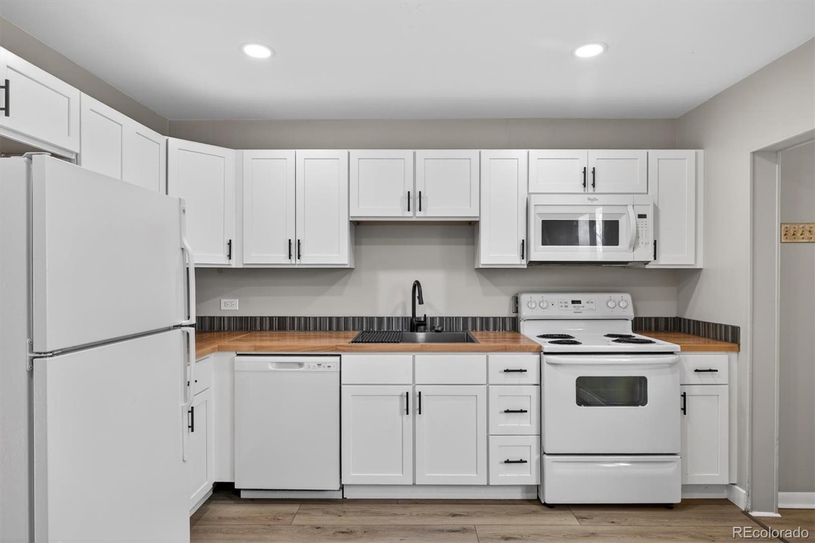 705 Perry Street Denver, CO 80204 - Photo 8 of 23 a kitchen with granite countertop white cabinets and white appliances