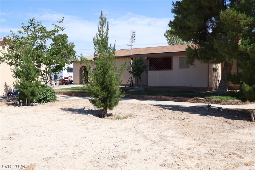 4501 East Kellogg Road Pahrump, NV 89061 - Photo 30 of 52 Mature trees frame the structure, offering shade and natural beauty to the property.