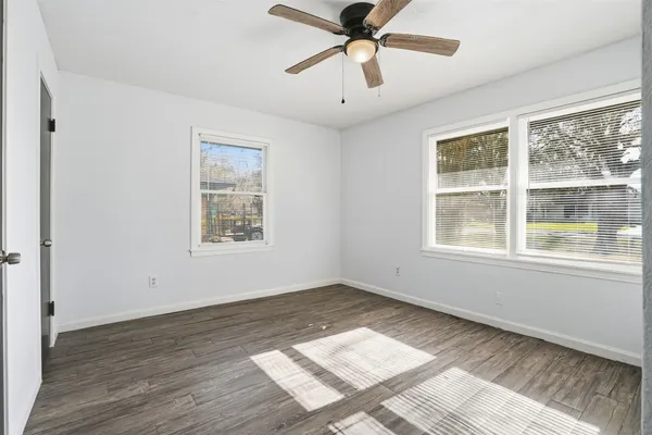 a view of an empty room with wooden floor and a window