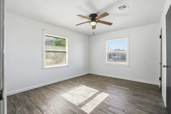 a view of empty room with wooden floor and fan