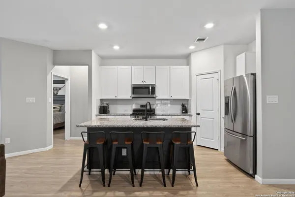 a kitchen with kitchen island granite countertop a refrigerator and a stove top oven