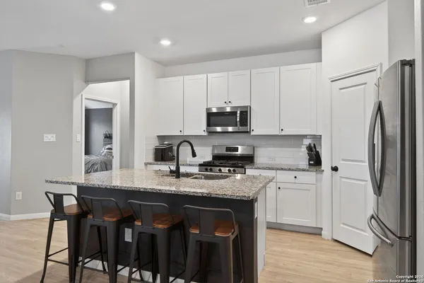 a kitchen with stainless steel appliances granite countertop a stove a refrigerator a sink a table and chairs