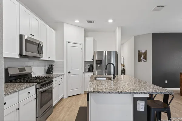 a kitchen with stainless steel appliances granite countertop a kitchen island hardwood floor sink stove and microwave