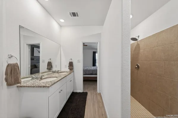 a en suite bathroom with a granite countertop sink and a mirror