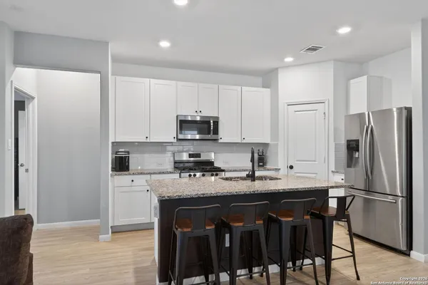 a kitchen with a refrigerator a stove a sink and white cabinets