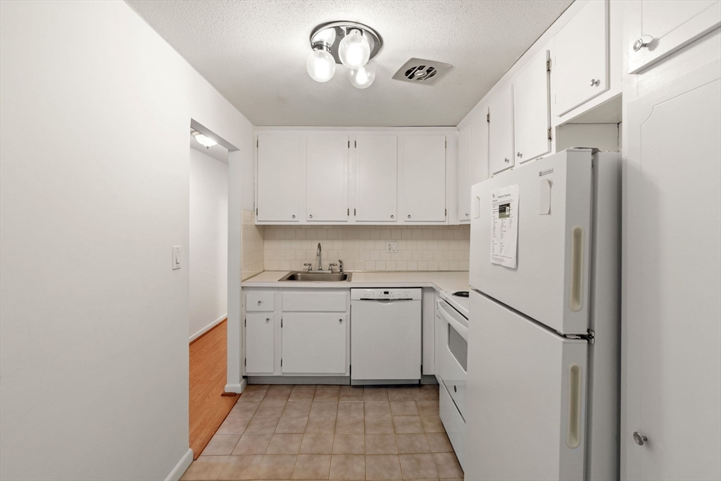 1 Colonial Drive, Unit B18 Andover, MA 01810 - Photo 8 of 25 a kitchen with white cabinets and white appliances
