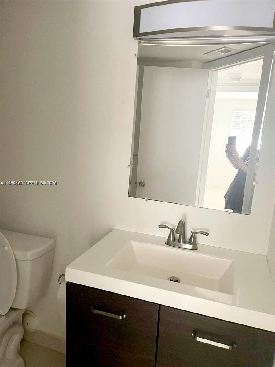 8821 Wiles Road, Unit 101 Coral Springs, FL 33067 - Photo 12 of 16 a bathroom with a sink a toilet and mirror