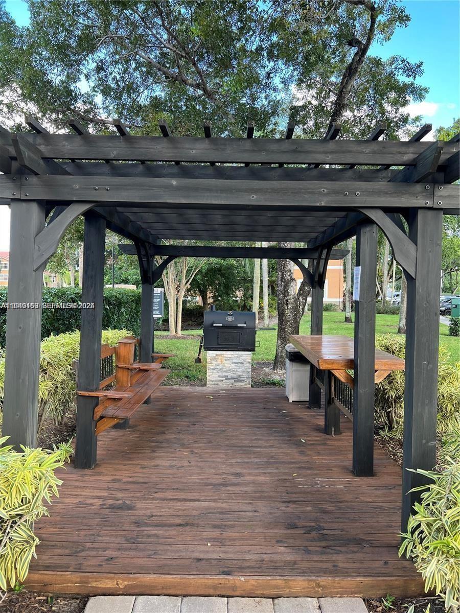 8821 Wiles Road, Unit 101 Coral Springs, FL 33067 - Photo 6 of 16 a view of a patio with table and chairs potted plants with wooden floor and floor to ceiling window