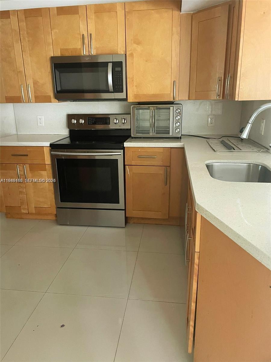 8821 Wiles Road, Unit 101 Coral Springs, FL 33067 - Photo 7 of 16 a kitchen with a stove a sink and a microwave