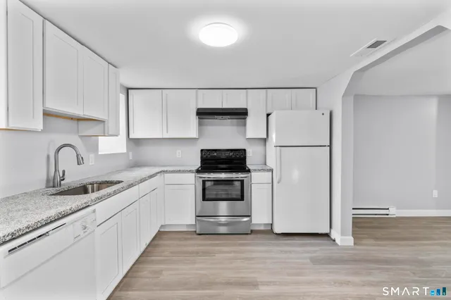 a kitchen with granite countertop white cabinets and white appliances