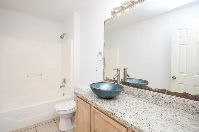 a bathroom with a granite countertop sink a toilet and bathtub