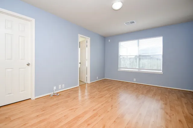 an empty room with wooden floor and windows