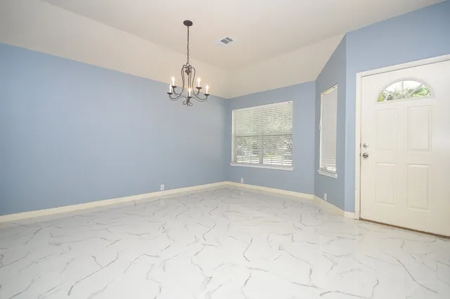 en empty room with windows and chandelier