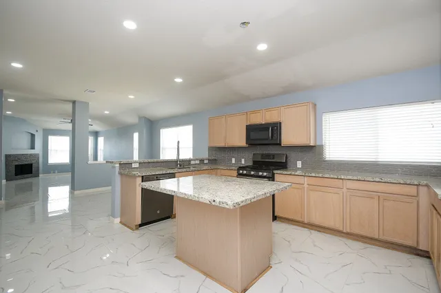 a large kitchen with granite countertop lots of counter top space appliances and a window