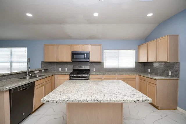 a kitchen with stainless steel appliances granite countertop a sink stove and cabinets