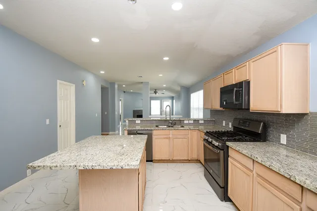 a large kitchen with granite countertop a sink and white cabinets