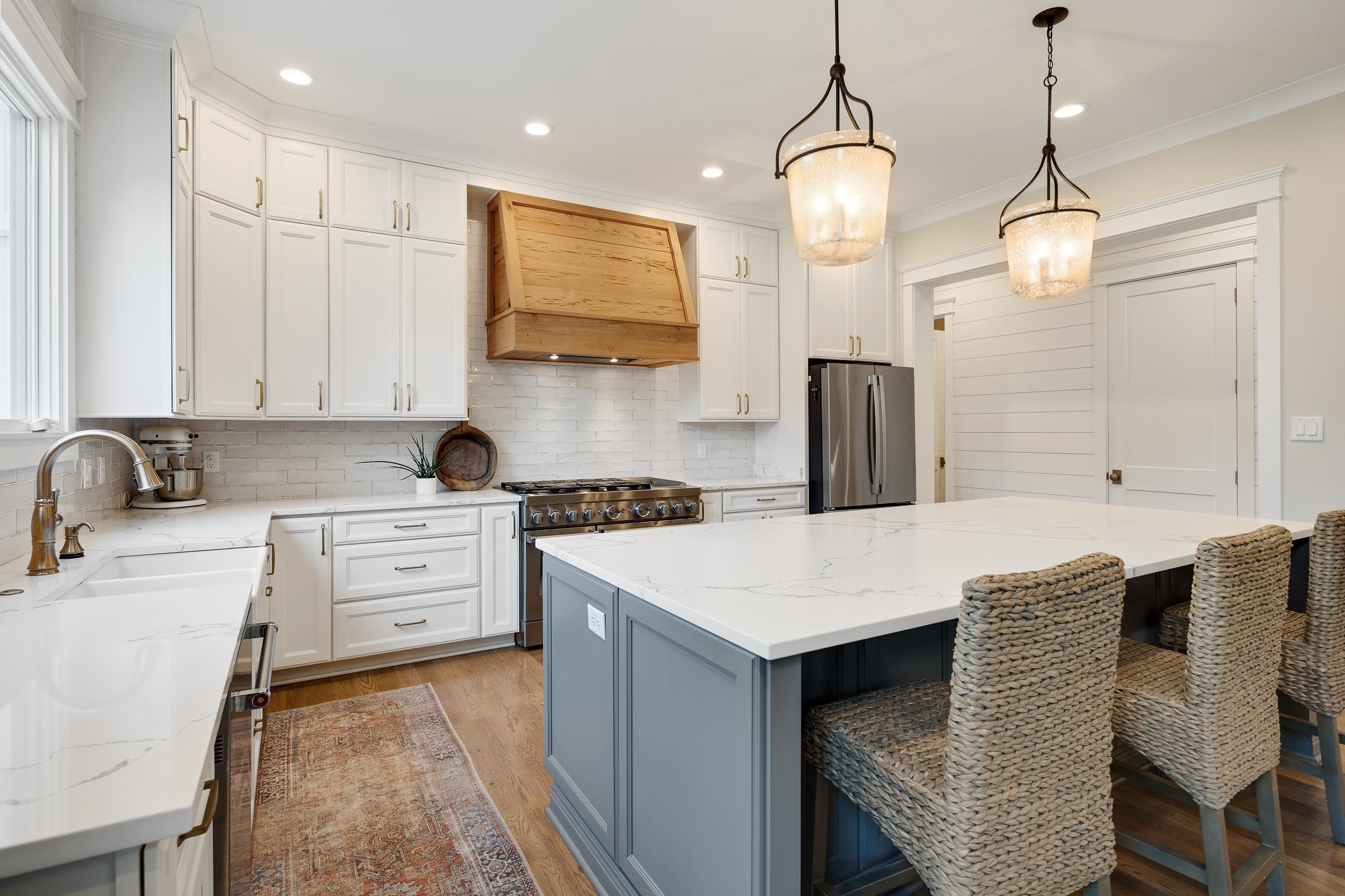 805 Shady Grove Road Williston, TN 38076 - Photo 12 of 40 Gourmet kitchen featuring white cabinetry, wood-finish range hood, stainless steel appliances, large center island with seating, and wood-finish flooring