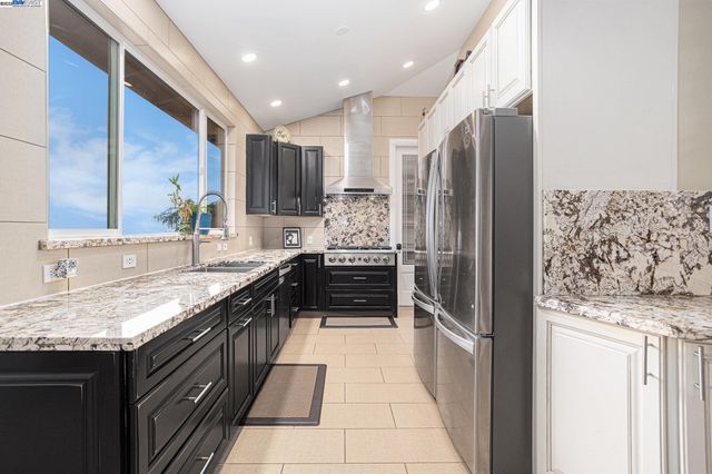 a large kitchen with stainless steel appliances granite countertop a sink stove and refrigerator
