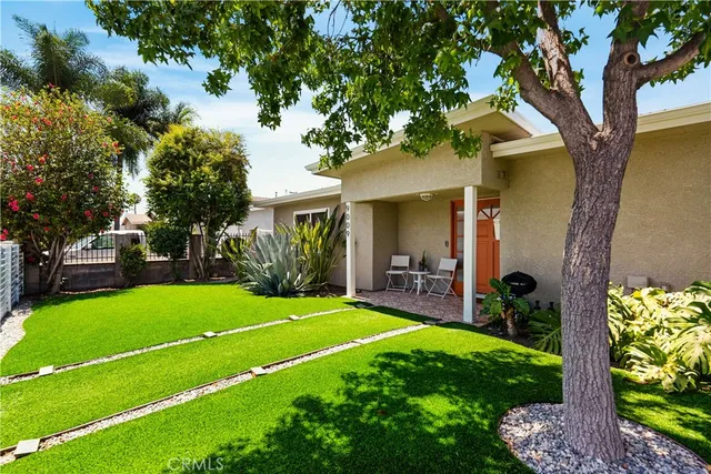 a view of a house with a backyard and a tree