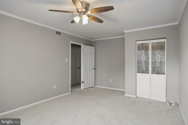 an empty room with closet and a ceiling fan