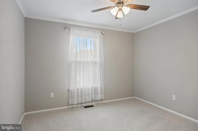 an empty room with a chandelier fan and windows