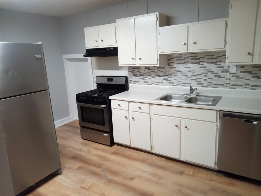 4500 Avenue D, Unit B Austin, TX 78751 - Photo 6 of 16 Kitchen with stainless steel appliances, light countertops, light wood-type flooring, white cabinets, and backsplash