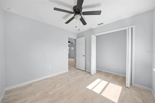 an empty room with closet and a ceiling fan