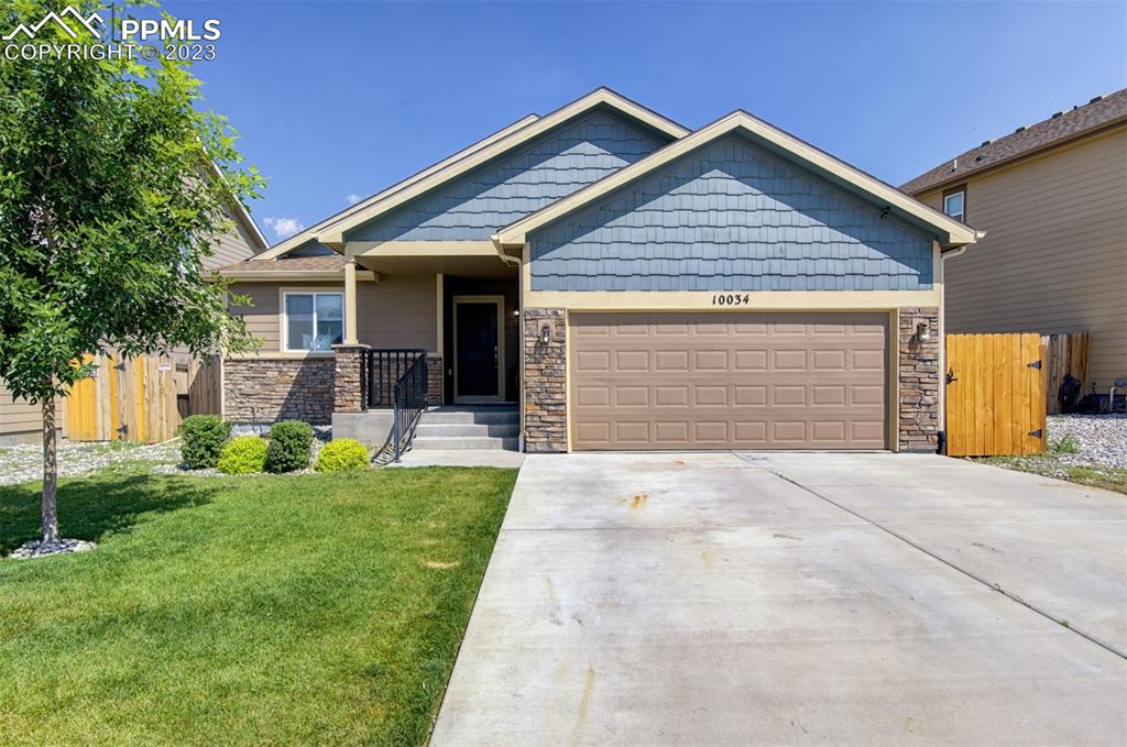 10034 Intrepid Way Colorado Springs, CO 80925 - Photo 1 of 31 a front view of a house with a yard and garage