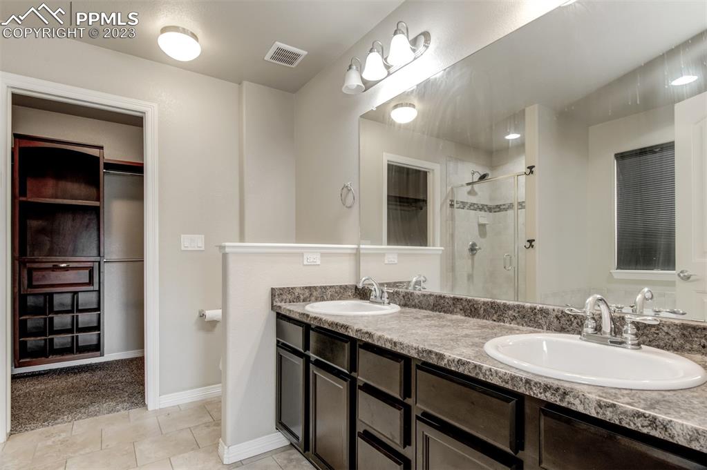 10034 Intrepid Way Colorado Springs, CO 80925 - Photo 16 of 31 a bathroom with a granite countertop sink a light fixture and a mirror