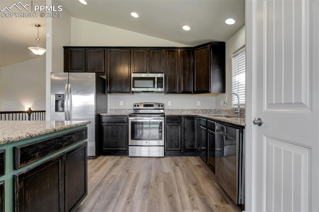 10034 Intrepid Way Colorado Springs, CO 80925 - Photo 8 of 31 a kitchen with stainless steel appliances kitchen island granite countertop a stove a sink and a refrigerator