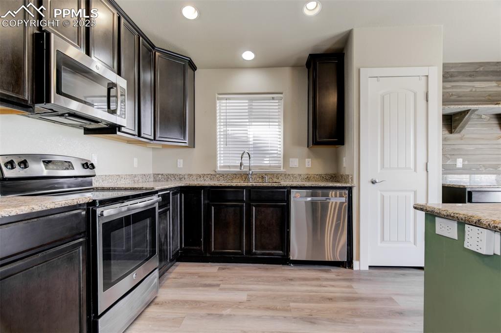 10034 Intrepid Way Colorado Springs, CO 80925 - Photo 9 of 31 a kitchen with stainless steel appliances granite countertop a stove a sink and a microwave