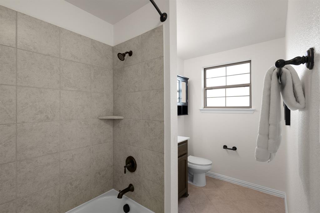 186 County Road 4430 Rhome, TX 76078 - Photo 31 of 40 a bathroom with a granite countertop toilet a sink and shower