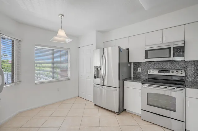a kitchen with cabinets stainless steel appliances and a window