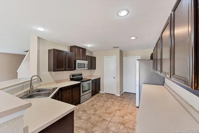a kitchen with granite countertop a sink stainless steel appliances and cabinets