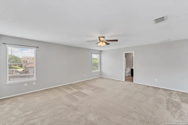 an empty room with windows and chandelier fan
