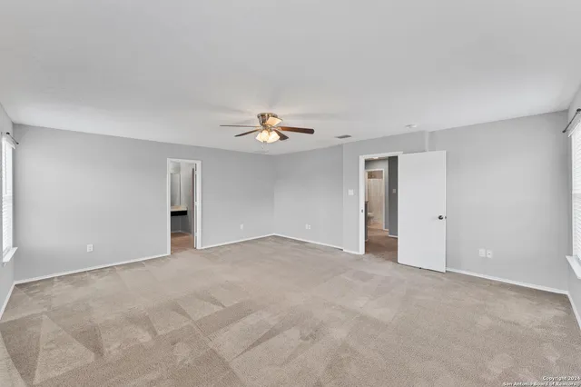 a view of an empty room with a chandelier fan