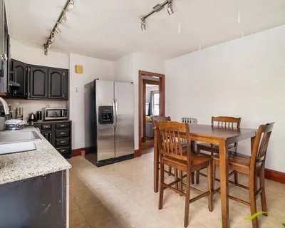 a kitchen with stainless steel appliances kitchen island granite countertop a table chairs microwave and refrigerator