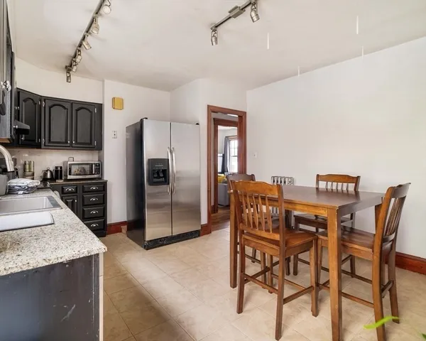a kitchen with stainless steel appliances kitchen island granite countertop a table chairs microwave and refrigerator