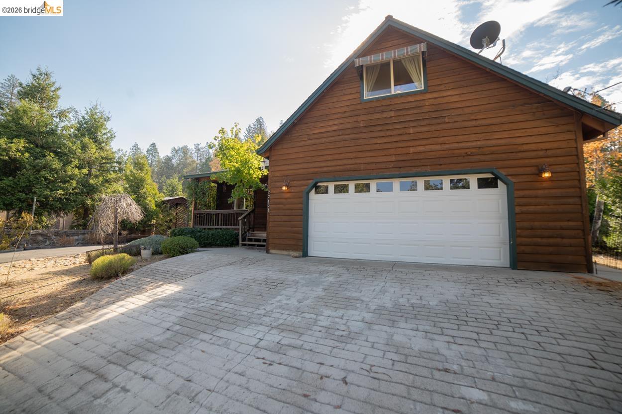 22401 Ridge Road Twain Harte, CA 95383 - Photo 48 of 52 Wood-sided exterior with an attached garage, featuring a stamped concrete driveway and a gabled roofline