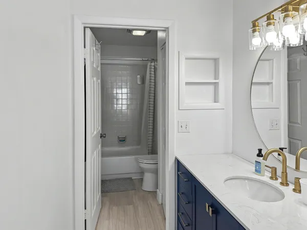 a bathroom with a granite countertop sink toilet and shower a mirror
