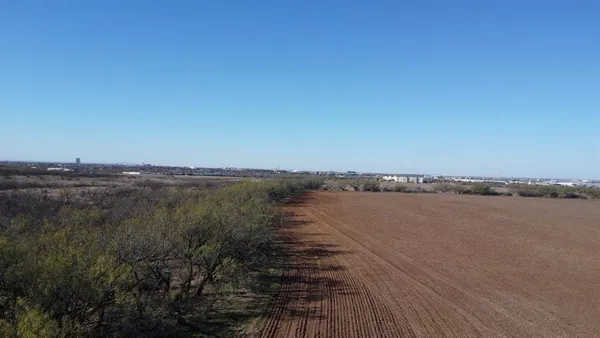 a view of a dry yard with wooden fence