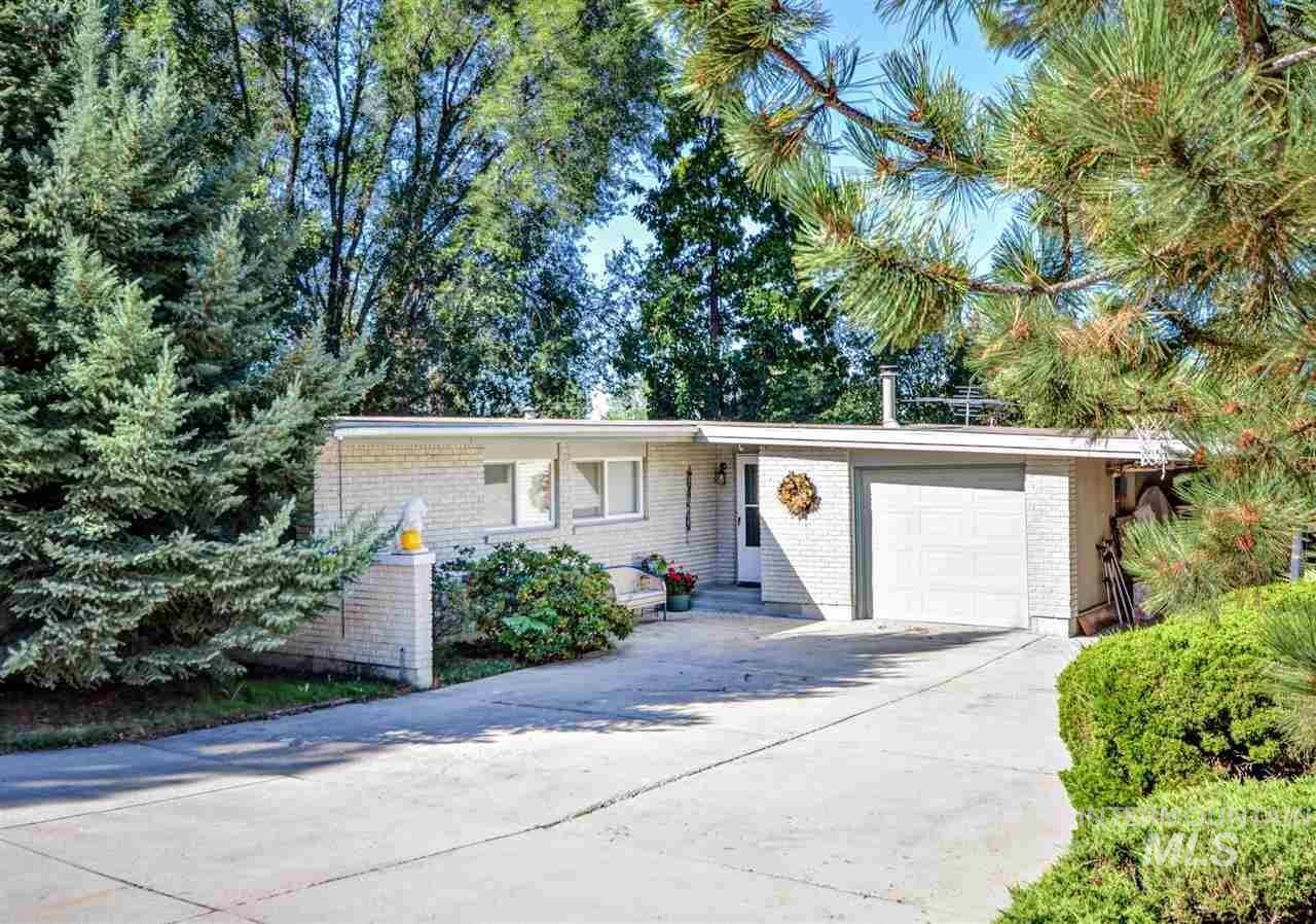 7141 West Hill Road Boise, ID 83714 - Photo 1 of 28 Exterior featuring gray brick siding, a paneled brown garage door, and a red entry door with a storm door