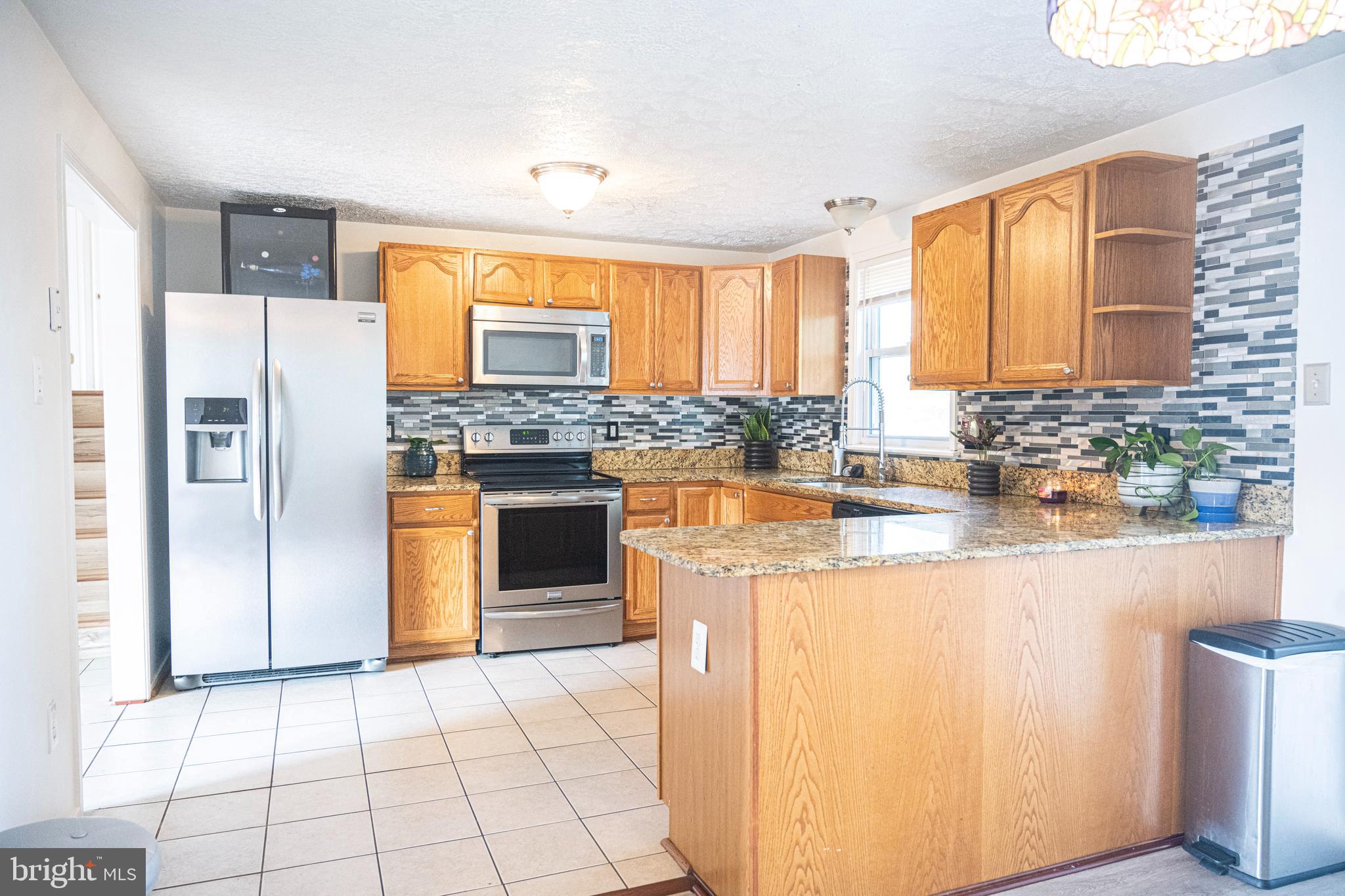 3115 Northmont Road Windsor Mill, MD 21244 - Photo 9 of 49 a kitchen with stainless steel appliances granite countertop a stove a refrigerator a sink and a microwave